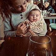 Agathe participe au concours pour gagner de l'argent avec cette photo : baby, woman, smile, cafe, indoor, table, glass, sweater, holding, people, restaurant, happy, portrait, seated, leopard_print, warm_lighting, background, face, person, love