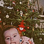 Agathe participe au concours pour gagner de l'argent avec cette photo : baby, celebration, child, christmas_tree, cozy, cute, decorations, face, festive, hand_in_mouth, holiday, home, indoors, infant, lights, ornaments, pink_clothing, seasonal, sitting, tree