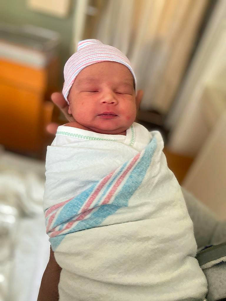 Darren is registered to the contest to win money with this photo: baby, baby_products, baby_safety, baby_sleeping, baby_toddler_clothing, cap, cheek, child, chin, comfort, curtain, face, hat, head, headwear, linens, outerwear, person, sitting, skin