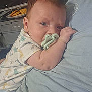 Thomas is registered to the contest to win money with this photo: baby, blue_shirt, chair, clothing, comfort, cute, face, hand, holding, indoor, infant, pacifier, person, printer, resting, sitting, snacks, table, water_bottle, young_child