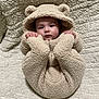 Walker is registered to the contest to win money with this photo: baby, teddy_bear, onesie, blanket, cute, infant, face, hands, hood, soft_texture, sleepwear, lying_down, child, warm_clothing, adorable, cozy, portrait, indoor, newborn, fuzzy