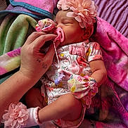 Amylah is registered to the contest to win money with this photo: baby, newborn, sleeping, pacifier, hand, flower_headband, floral_outfit, mittens, socks, blanket, colorful, soft_texture, infant, cute, resting, toddler, person, bed, comfort, peaceful