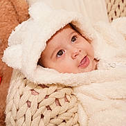 Melody joined the competition — help win amazing prizes! baby, infant, child, portrait, smiling, happy, face, eyes, open_mouth, hood, blanket, knitted_blanket, white_clothing, cozy, soft_texture, indoor, warm_lighting, teddy_bear, close_up, cuddly