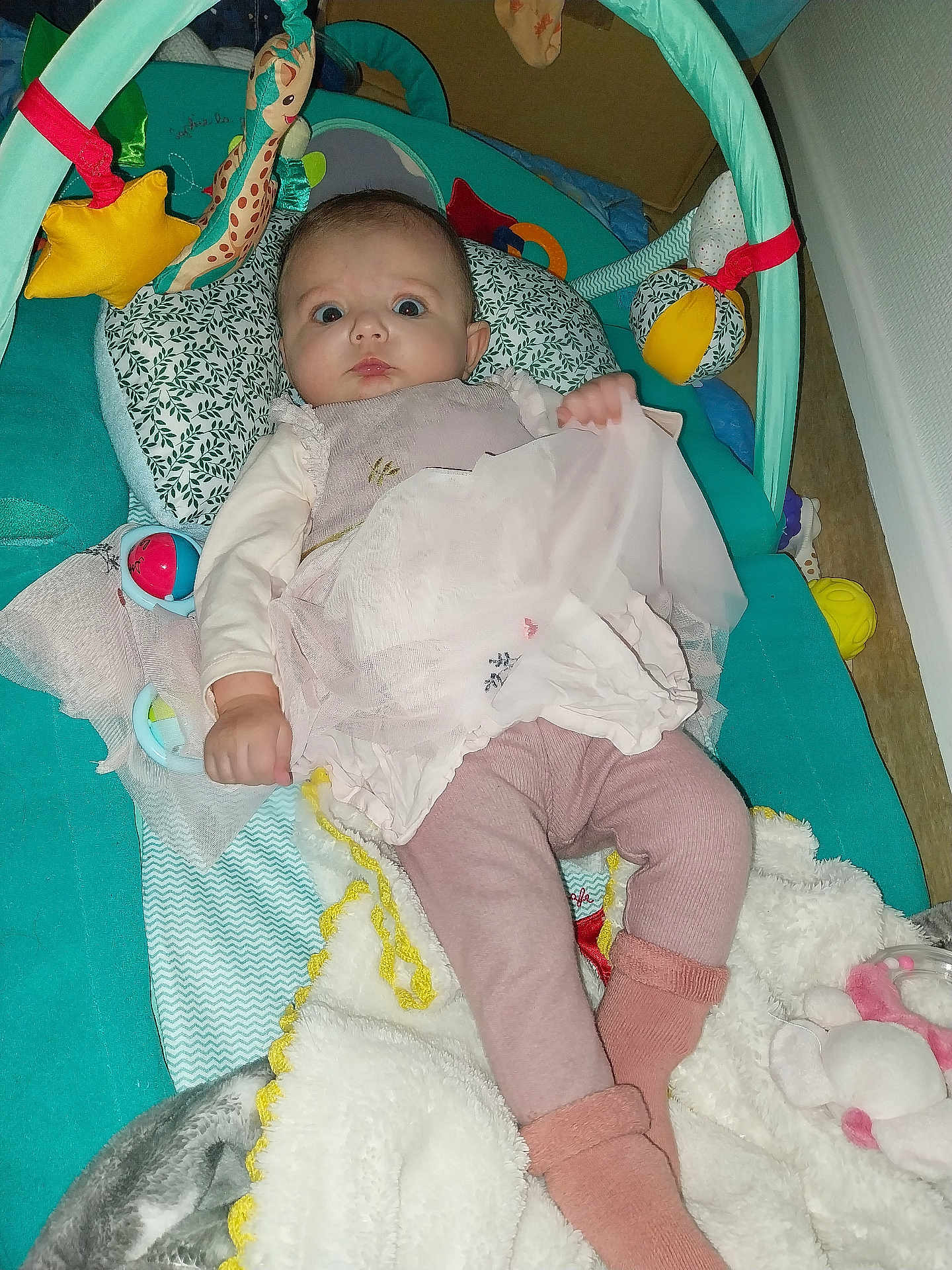 Pauline participe au concours pour gagner de l'argent avec cette photo : baby, infant, play_gym, toy, blanket, soft_toy, pink_clothing, leggings, socks, pillow, floor, indoor, child, cute, curious, baby_girl, plush, comfort, lying_down, home