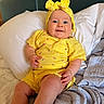 baby, child, yellow_clothing, headband, smile, bed, pillow, blanket, infant, cute, indoors, happy, person, portrait, sitting, soft_texture, comfortable, bright_colors, young_child, casual