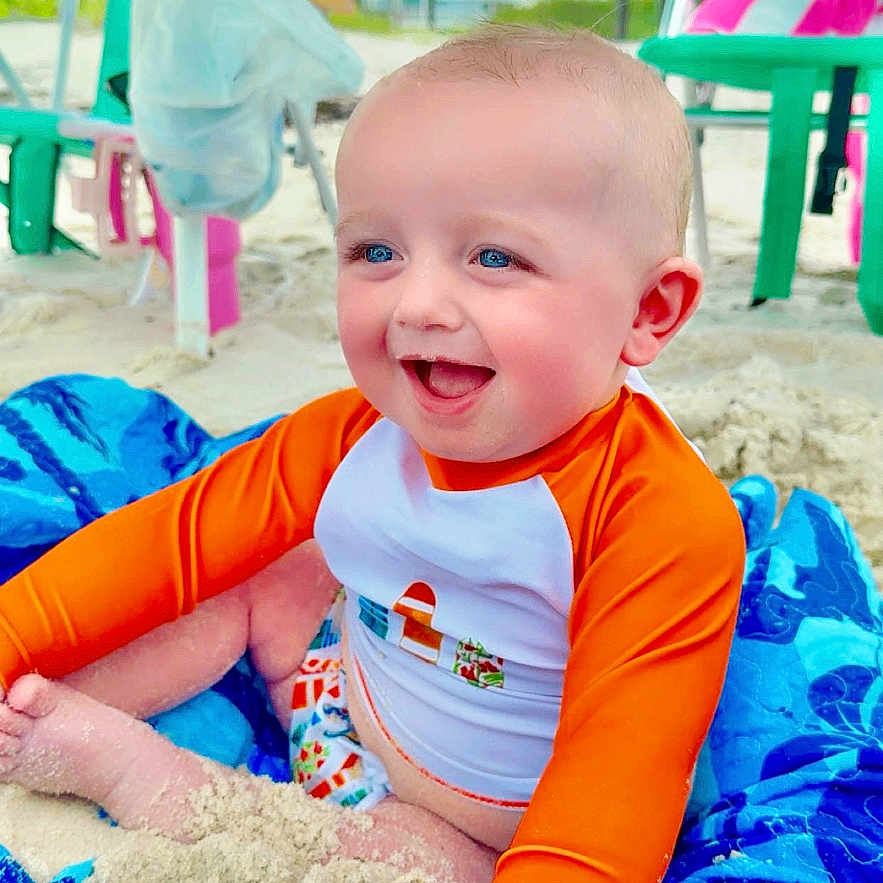 Heston joined the competition — help win amazing prizes! baby, beach, blue_eyes, casual, child, daytime, footwear_free, happy, orange_shirt, outdoor, person, playful, sand, sand_play, sitting, smiling, summer, sunny, towel, vacation