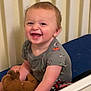 toddler, child, smiling, happy, stuffed_animal, toy, crib, bed, baby_clothes, short_sleeve_shirt, indoor, person, face, head, hair, skin, furniture, playtime, cute, joyful