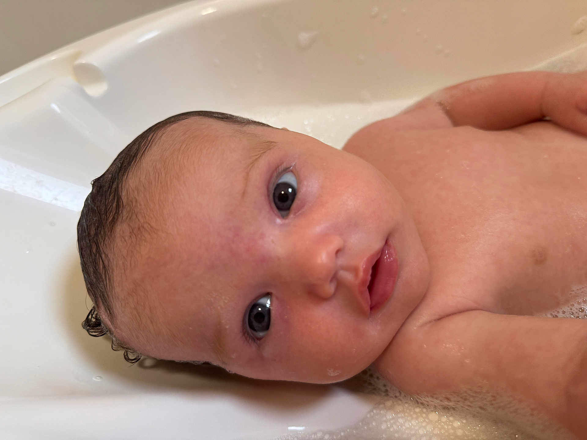 Ivy is registered to the contest to win money with this photo: baby, bathtub, water, soap_bubbles, skin, face, eyes, infant, wet_hair, bath_time, child, cute, portrait, close_up, curious, young, human, indoors, bath, clean
