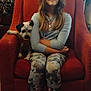 armchair, barefoot, carpet, casual, child, clothing, curtain, dog, furniture, girl, home, indoor, long_hair, patterned_pants, pet, pile_of_clothes, portrait, relaxed, room, smile