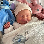 Ava participe au concours pour gagner de l'argent avec cette photo : newborn, baby, sleeping, hat, blanket, plush_toy, stitch, pink_bunny, hospital_bassinet, cozy, soft, cute, infant, child, smile, wrapped, bed, resting, comfort, peaceful