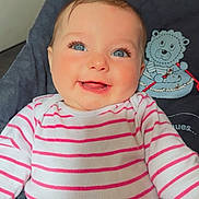 Maëlyss a rejoint le concours — aidez-le/la à gagner de superbes lots ! baby, smiling, blue_eyes, striped_clothing, onesie, infant, happy, cute, face, portrait, child, seated, indoors, cushion, plush_toy, clothing, person, closeup, cheerful, young_child