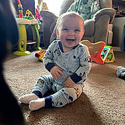 Esmae joined the competition — help win amazing prizes! baby, smiling, pajamas, carpet, living_room, armchair, blanket, toys, dog, floor, window, natural_light, child, happy, indoor, cute, playful, pet, furniture, cozy