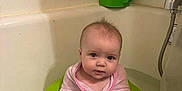 Esmae is registered to the contest to win money with this photo: baby, towel, bathtub, bath, green_bath_seat, infant, child, water, pink, wrapped, cute, indoor, plumbing, fixture, tap, wall, face, person, bathroom, sitting