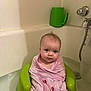 baby, towel, bathtub, bath, green_bath_seat, infant, child, water, pink, wrapped, cute, indoor, plumbing, fixture, tap, wall, face, person, bathroom, sitting