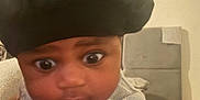 Tamaramiyen is registered to the contest to win money with this photo: baby, black_bonnet, child, closeup, clothing, cozy, curious, cute, face, fleece, headwear, indoor, infant, neutral_background, person, portrait, seated, soft_lighting, wide_eyes, young_child
