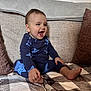 toddler, child, smiling, laughing, blue_clothing, stars_pattern, sitting, couch, blanket, pillows, indoors, happy, baby, foot, hand, face, cozy, home, portrait, casual
