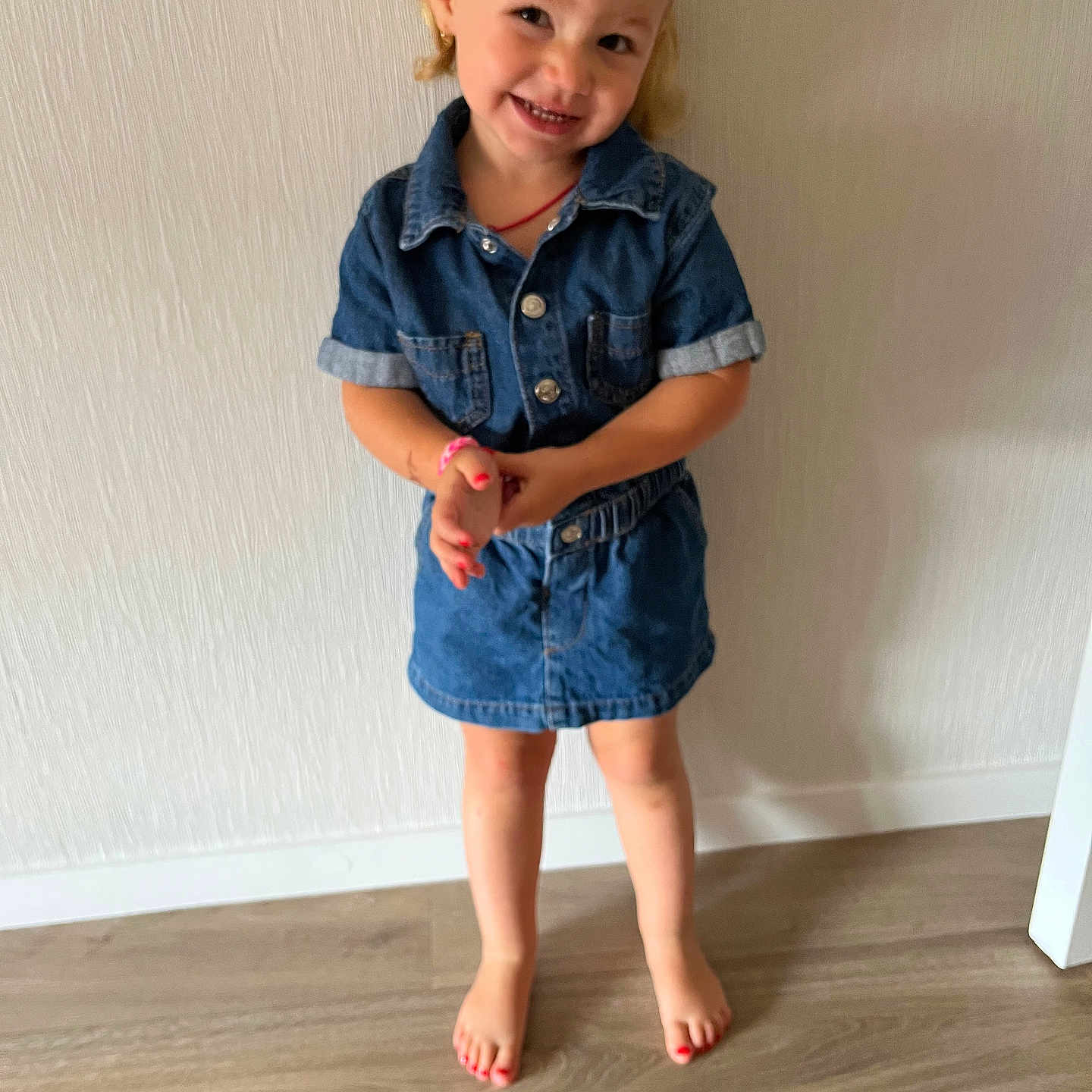 Nelya participe au concours pour gagner de l'argent avec cette photo : barefoot, casual_clothing, child, cute, denim, dress, fashion, floor, girl, hair_bow, happy, indoors, person, playful, portrait, skin, smile, standing, wooden_floor, young