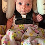 baby, blanket, car_seat, child, colorful, curious_expression, cushion, cute, indoor, infant, looking_at_camera, newborn, person, pink_headband, portrait, safety_harness, seat_belt, soft_texture, wide_eyes, wrapped