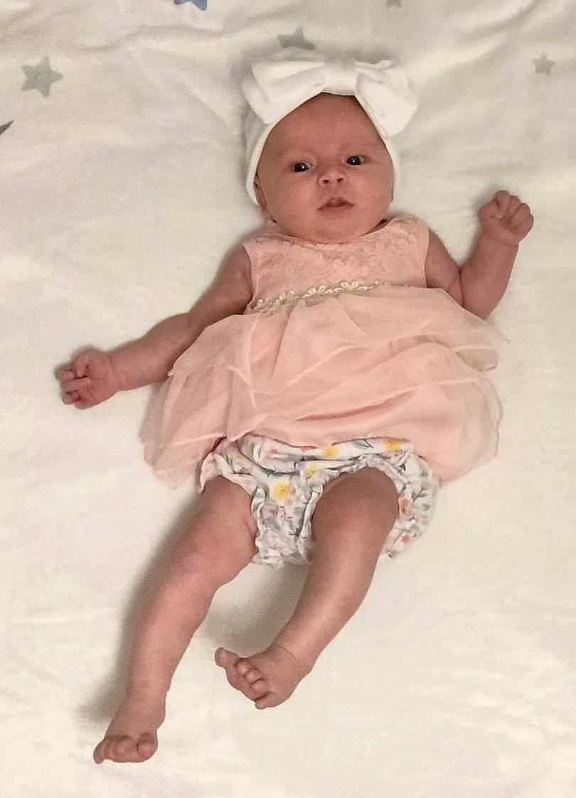 Caroline is registered to the contest to win money with this photo: baby, baby_toddler_clothing, barefoot, cheek, child, dress, foot, fun, happy, human_body, human_leg, pattern, peach, person, pink, sitting, skin, sleeve, smile, thigh