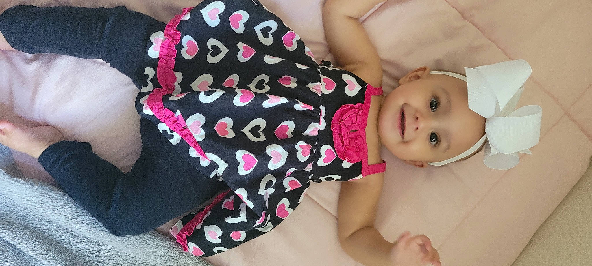 Chanel is registered to the contest to win money with this photo: arm, baby, baby_toddler_clothing, comfort, dress, facial_expression, finger, hand, happy, headgear, headwear, joint, joy, neck, person, pink, shoulder, skin, sleeve, smile
