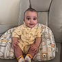 baby, child, infant, smiling, sitting, pillow, animal_print, leather_chair, yellow_outfit, short_sleeves, socks, cute_hair, indoors, happy, portrait, young_child, palm_tree_pattern, hand, skin, furniture