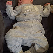 Tommy is registered to the contest to win money with this photo: baby, sleeping, sweatshirt, sweatpants, under_armour, socks, couch, indoor, child, relaxing, cozy, infant, clothing, person, rest, casual, soft, comfort, young_child, peaceful