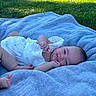 Eliana joined the competition — help win amazing prizes! baby, blanket, blue, outdoor, grass, smile, infant, relaxed, sunlight, texture, person, skin, face, clothing, cute, lying_down, daylight, nature, happy, small