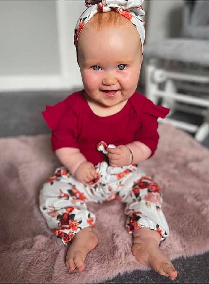 Lea is registered to the contest to win money with this photo: baby, baby_toddler_clothing, child, eye, face, fun, happy, head, headband, joy, pattern, person, photograph, pink, red, sitting, skin, sleeve, smile, standing
