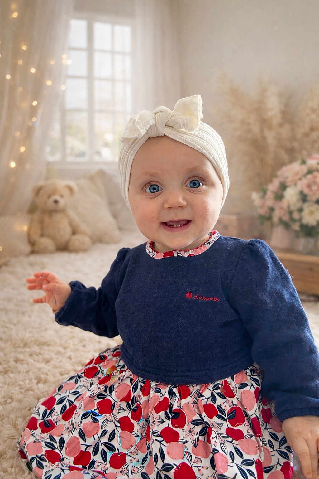 Mahyna participe au concours pour gagner de l'argent avec cette photo : baby, infant, blue_eyes, headband, bow, floral_dress, patterned_skirt, long_sleeves, sitting, smiling, rosy_cheeks, plush_toy, teddy_bear, nursery, window_light, curtains, fairy_lights, shaggy_rug, indoor, cozy_room