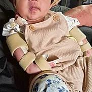 Emiliano joined the competition — help win amazing prizes! baby, child, infant, portrait, cowboy_hat, straw_hat, sitting, indoors, person, face, wide_eyed, clothing, overalls, shirt, sock, floral_pattern, adult_arm, chair, close_up, funny_expression