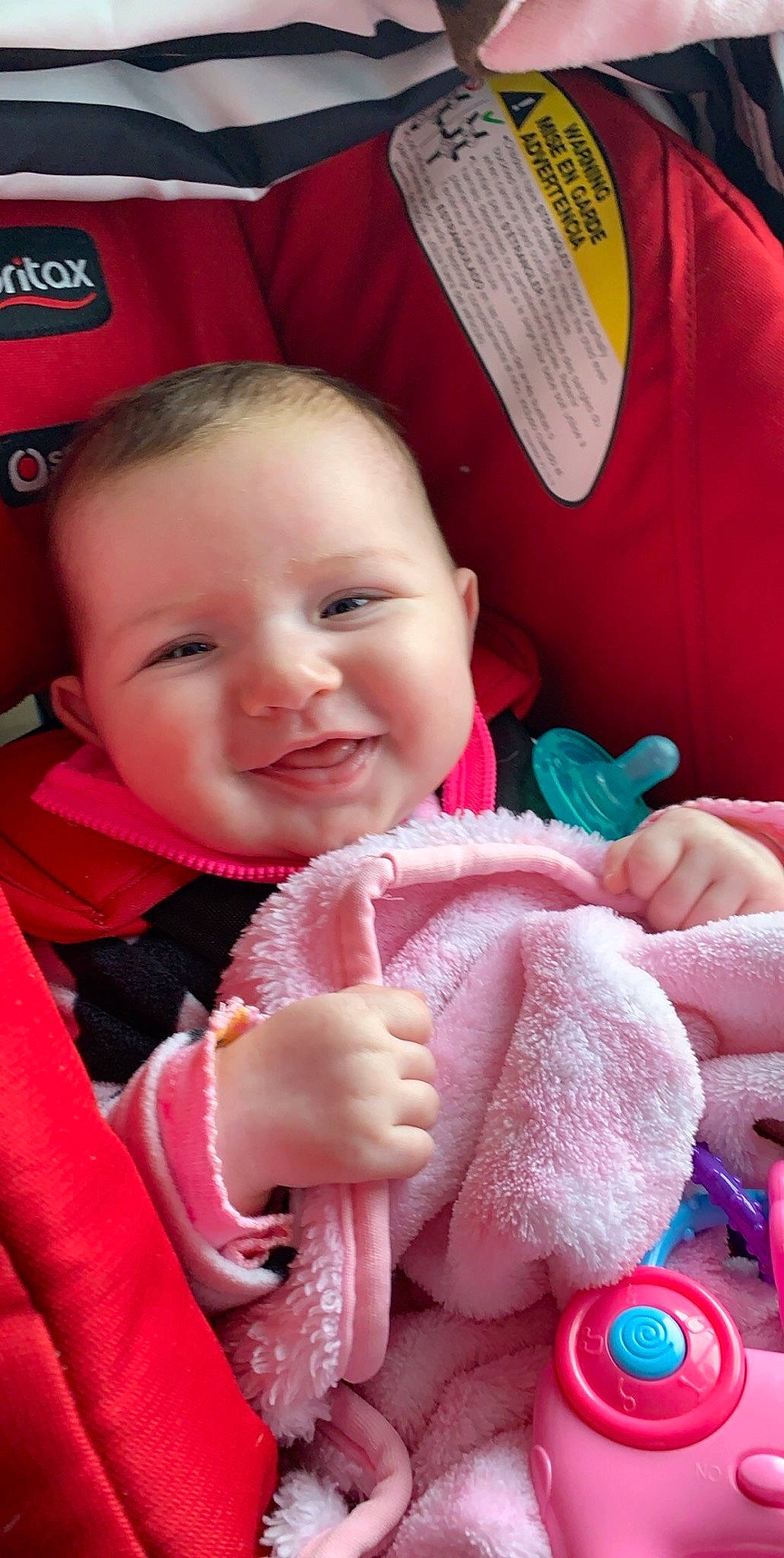 Hadley is registered to the contest to win money with this photo: baby, car_seat, cheek, child, joy, mouth, nose, person, pink, plush, skin, smile, stuffed_toy, toddler