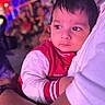 Aadvik joined the competition — help win amazing prizes! adult, baby, blurred_background, celebration, child, closeup, colorful_lights, crowd, curious, event, expression, face, holding, indoors, people, person, portrait, red_jacket, warmth, white_sleeve