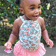 Jade joined the competition — help win amazing prizes! toddler, child, girl, smiling, standing, outdoor, hair_clips, pacifier, concrete, floral_top, pink_skirt, sparkly_shoes, happy, cute, person, young_child, nature, greenery, sunlight, playful