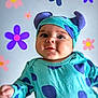 baby, child, blue_clothing, hat, purple_spots, face, smiling, cheeks, background, flowers, cartoon_flowers, playful, cute, infant, portrait, headwear, studio, closeup, happy, person