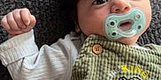 Kamillo is registered to the contest to win money with this photo: baby, blanket, button, child, closeup, cute, expression, eyes, face, green_clothing, hand, indoors, infant, lying_down, overalls, pacifier, portrait, soft_lighting, textile, young