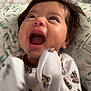 baby, infant, laughing, smiling, monkey_pattern, onesie, clothing, face, hands, hair, cushion, leaf_pattern, indoor, closeup, portrait, child, happy, joyful, expression, toddler