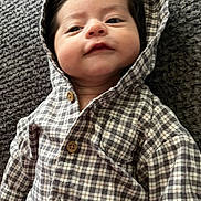 Kamillo is registered to the contest to win money with this photo: apparel, baby, buttons, child, cozy, cute, fabric, face, hair, hooded_clothing, indoors, infant, lying_down, pattern, plaid, portrait, smile, textured_surface, warm, young_child