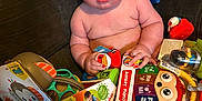 Blaine joined the competition — help win amazing prizes! baby, child, toy, toys, mickey_mouse, plush_toy, box, packaging, couch, indoor, person, cute, chubby, infant, colorful, sitting, holding, expression, red_toy, playful