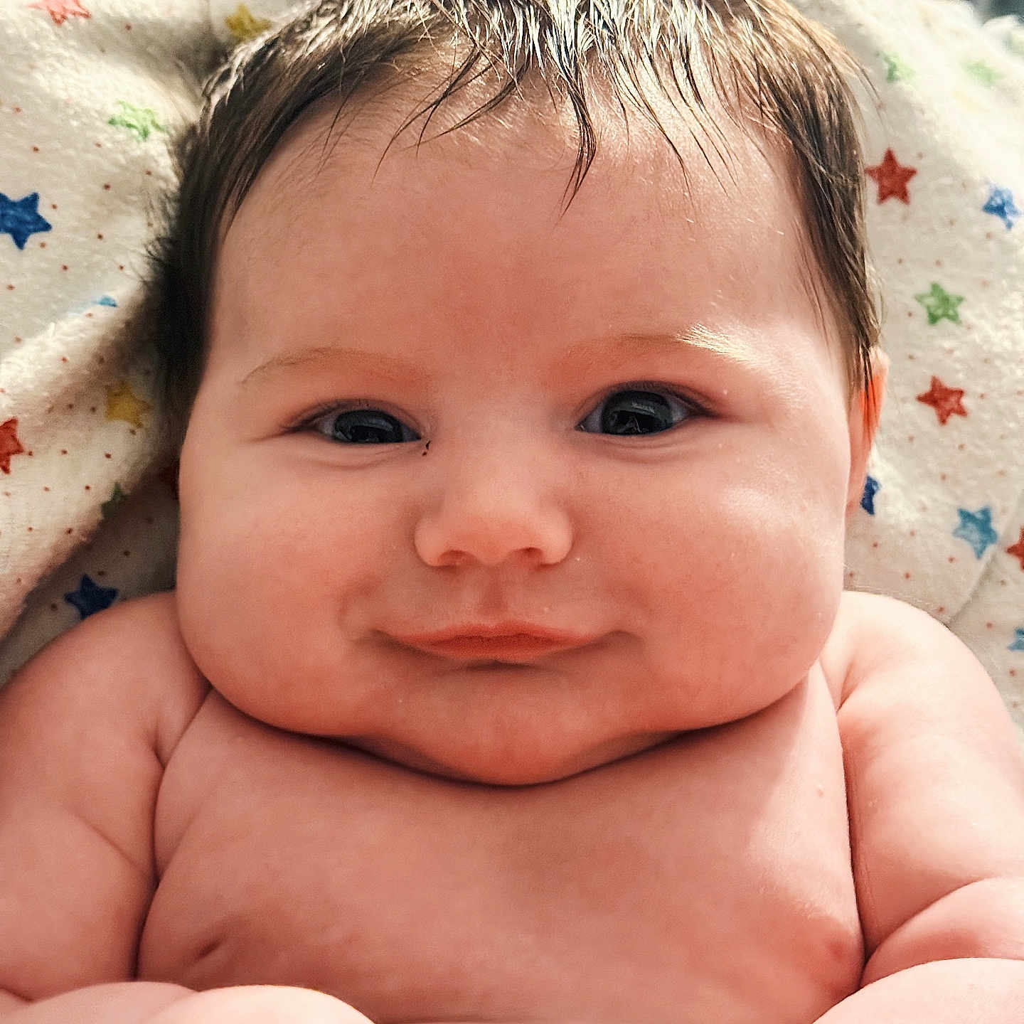 Cruz is registered to the contest to win money with this photo: baby, infant, smile, face, cheeks, skin, hair, blanket, pattern, stars, closeup, portrait, cute, child, newborn, happy, indoors, soft, expression, human