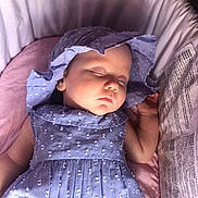 Ivy is registered to the contest to win money with this photo: baby, sleeping, blue_dress, bonnet, infant, cushion, pink_blanket, face, peaceful, child, soft_lighting, indoors, portrait, resting, cute, newborn, clothing, headwear, closeup, young_child