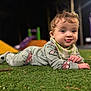 Abigail is registered to the contest to win money with this photo: baby, child, grass, playground, night, outdoor, cute, infant, clothing, bib, face, expression, toy, colorful, blurred_background, young_child, lying_down, curious, play, soft_lighting