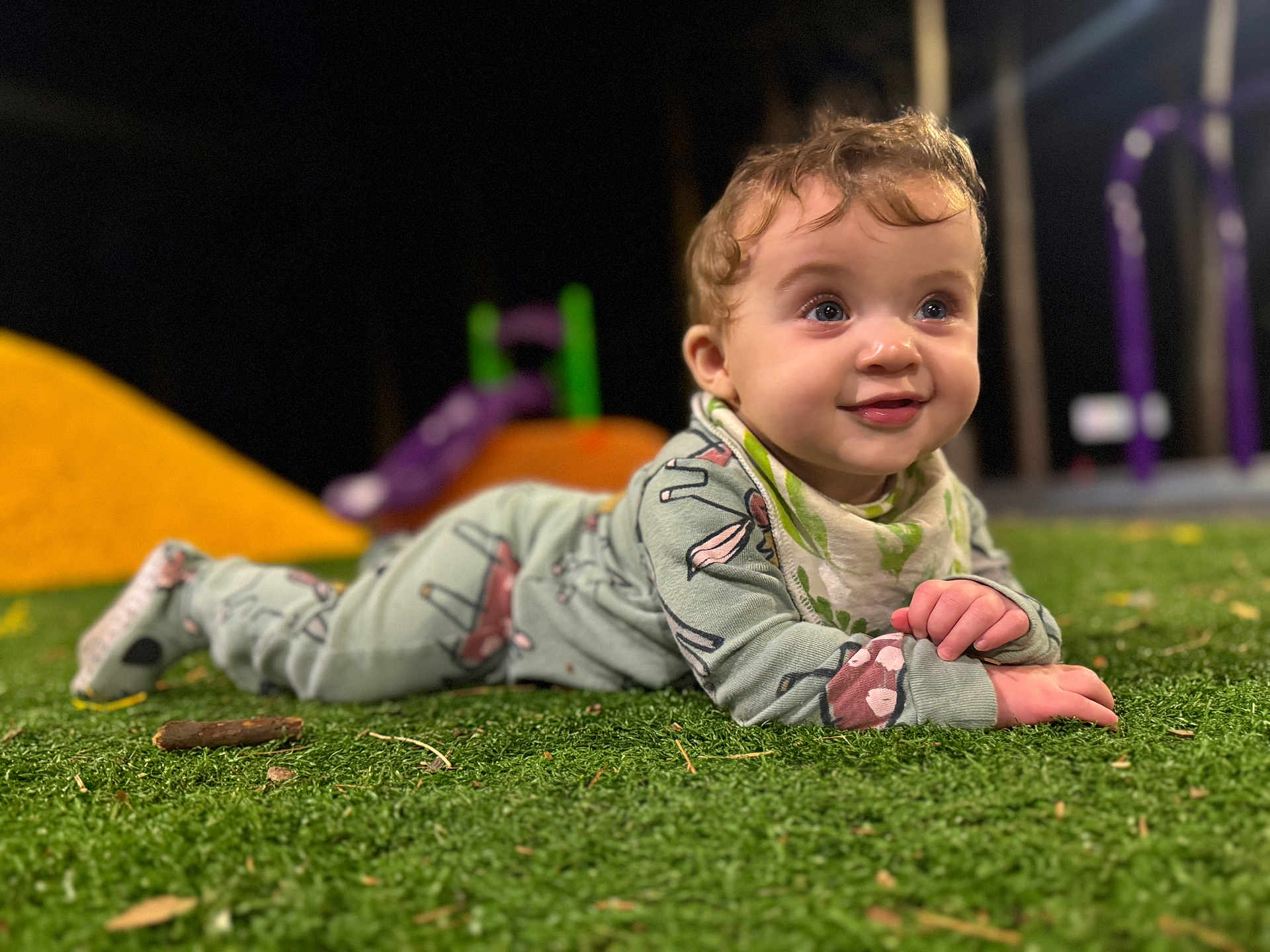 Abigail is registered to the contest to win money with this photo: baby, child, grass, playground, smiling, curly_hair, outdoor, toy, clothing, infant, face, person, play_equipment, green, purple, yellow, happy, toddler, cute, fun
