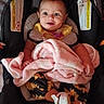 baby, car_seat, blanket, infant, child, clothing, footwear, happy, face, person, sitting, indoors, yellow, pink, patterned, smile, cute, young, seatbelt, comfort
