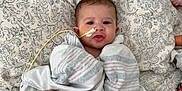 Kamari joined the competition — help win amazing prizes! baby, infant, blanket, bed, medical_tube, feeding_tube, face, child, patterned_bedspread, striped_blanket, laying_down, cute, young_child, hospital, healthcare, person, skin, head, expression, indoors