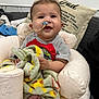 baby, infant, nasal_tube, blanket, smile, face, child, indoor, cushion, inflatable_chair, dinosaur_pattern, clothing, feet, comfort, healthcare, happy, person, cute, toddler, seated