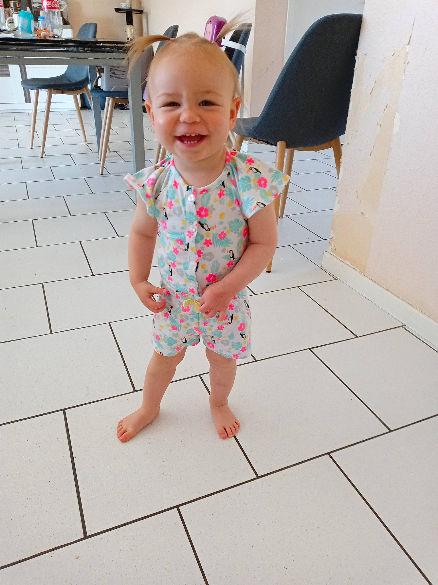 Amalia participe au concours pour gagner de l'argent avec cette photo : baby_toddler_clothing, chair, dress, eye, facial_expression, floor, flooring, fun, happy, head, joint, joy, line, person, pink, skin, sleeve, smile, standing, table