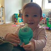 Saphira joined the competition — help win amazing prizes! toddler, child, sippy_cup, indoor, living_room, carpet, toy, window, curtains, american_flag, furniture, smiling, person, baby, play, home, cute, young_child, hand, face