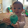 toddler, child, sippy_cup, indoor, living_room, carpet, toy, window, curtains, american_flag, furniture, smiling, person, baby, play, home, cute, young_child, hand, face