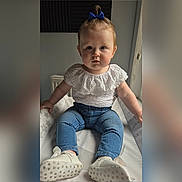 Miley joined the competition — help win amazing prizes! baby, child, infant, blue_bow, white_top, jeans, shoes, indoor, sitting, curious, face, person, footwear, cute, portrait, young_child, human, apparel, casual_clothing, closeup