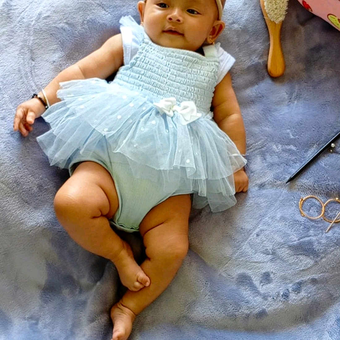 Liya is registered to the contest to win money with this photo: baby, blanket, bow, cartoon, child, clothing, cute, dog, glasses, hairbrush, headband, indoors, infant, lying_down, pen, pillow, plush, smiling, soft_texture, tutu